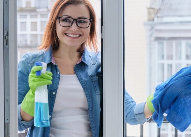Intervenante nettoyant une surface près d'une fenêtre